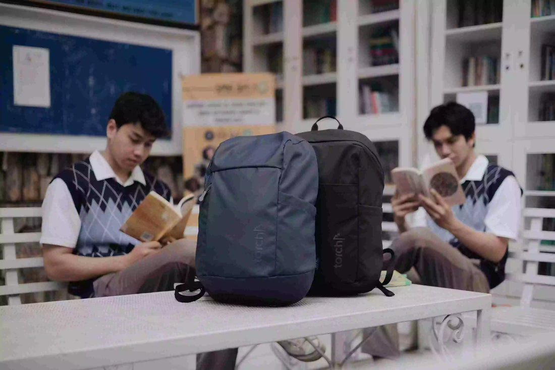 dua tas sekolah dari torch dengan latar belakang dua anak sekolah yang sedang membaca buku