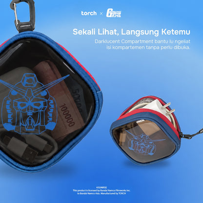 A blue translucent zippered pouch with red trim and a black carabiner clip, shown open and closed on a blue gradient background. The pouch has a dark interior compartment and a blue Gundam helmet graphic printed on the front.