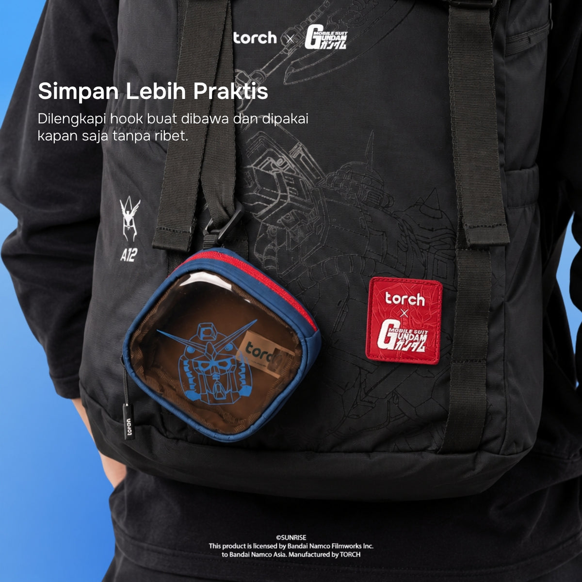 A black tactical backpack with a red and blue Gundam-themed pouch attached to the front, worn by a person against a blue background. White and red text and logos are printed on the bag.