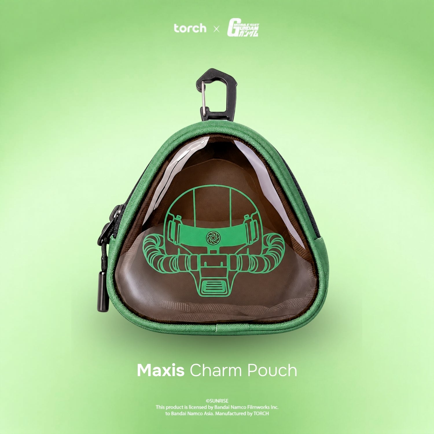 A green triangular charm pouch with a clear front window showing a brown plush character inside, set against a light green gradient background. The top features a black plastic carabiner, and the bottom displays the text 'Maxis Charm Pouch'.