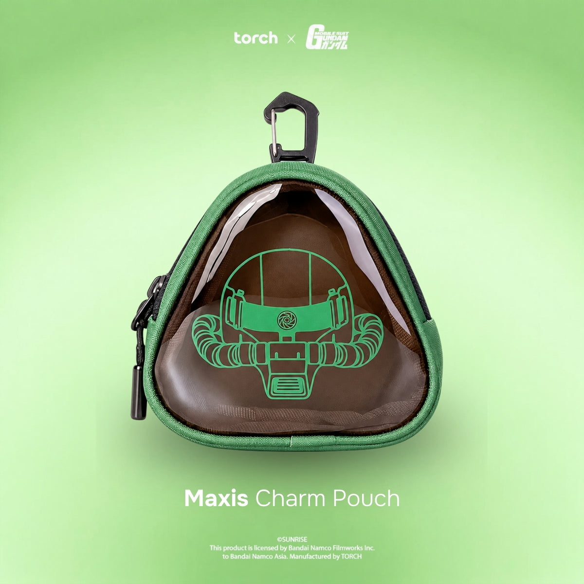 A green triangular charm pouch with a clear front window showing a brown plush character inside, set against a light green gradient background. The top features a black plastic carabiner, and the bottom displays the text 'Maxis Charm Pouch'.