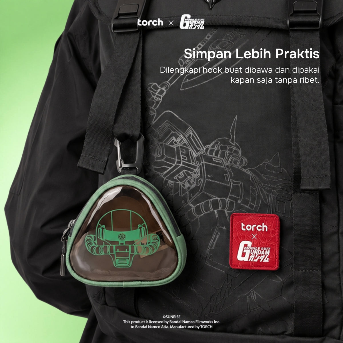 A black backpack featuring a Gundam-themed print, with a green-trimmed triangular clear pouch containing a green robot graphic, plus a red 'torch x G-Generation' patch. White promotional text is overlaid on the image against a light green gradient background.