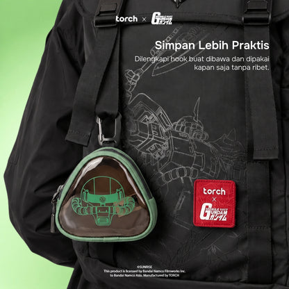 A black backpack featuring a Gundam-themed print, with a green-trimmed triangular clear pouch containing a green robot graphic, plus a red 'torch x G-Generation' patch. White promotional text is overlaid on the image against a light green gradient background.