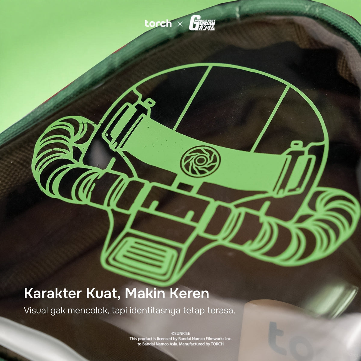 A close-up of a dark green and black backpack or pouch with a neon green line-art graphic of a helmet or mask. White text at the bottom reads 'Karakter Kuat, Makin Keren' with smaller descriptive copy below.