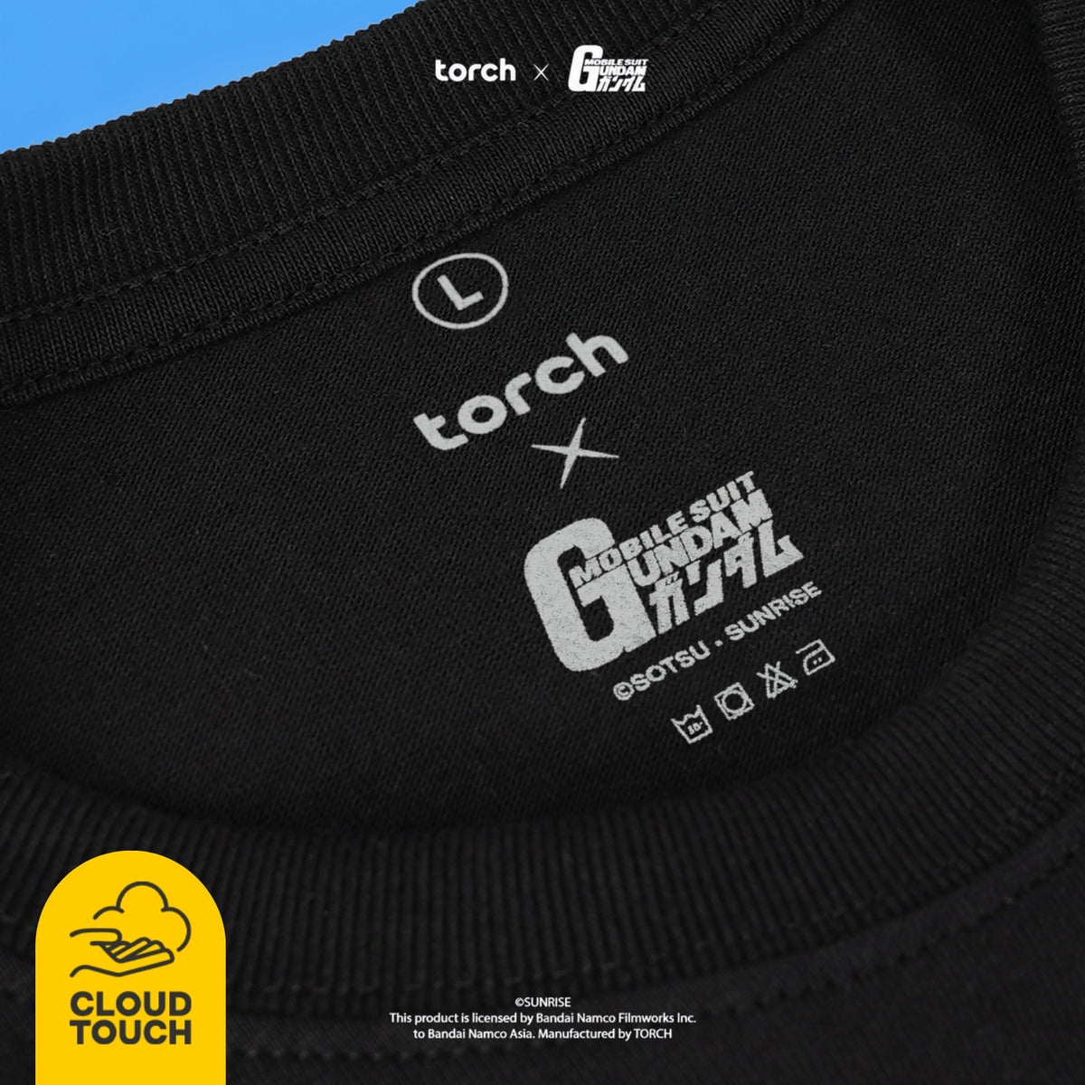Close-up of a black crewneck t-shirt collar showing a white printed graphic of the 'Torch x Mobile Suit Gundam' collaboration, featuring the text 'Mobile Suit Gundam'
