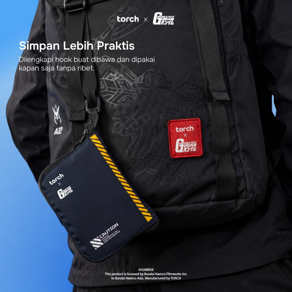 A black Torch x G-1000 crossbody bag worn over a black jacket, with a matching black pouch hanging at the side. The pouch has a red square Torch x G-1000 patch and white branding, and the main bag has subtle tonal graphics and a red patch.