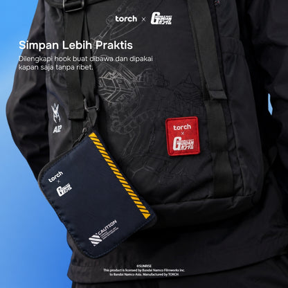 A black Torch x G-1000 crossbody bag worn over a black jacket, with a matching black pouch hanging at the side. The pouch has a red square Torch x G-1000 patch and white branding, and the main bag has subtle tonal graphics and a red patch.